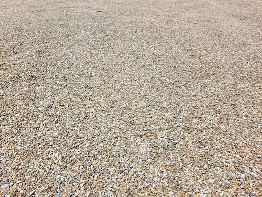 Wide expanse of freshly spread tan decorative gravel across a graded yard