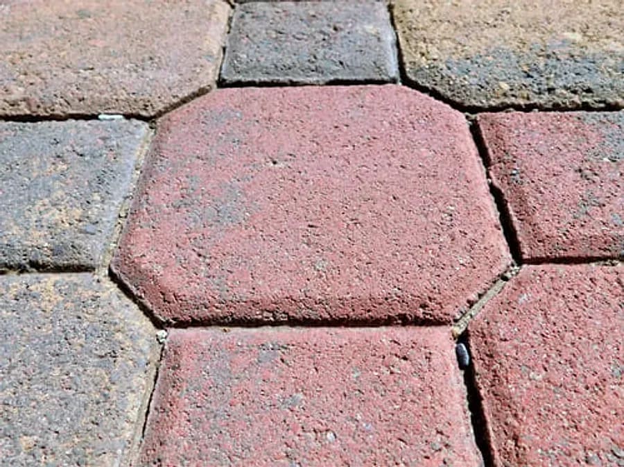 Close-up of interlocking concrete pavers in a red and grey patio surface