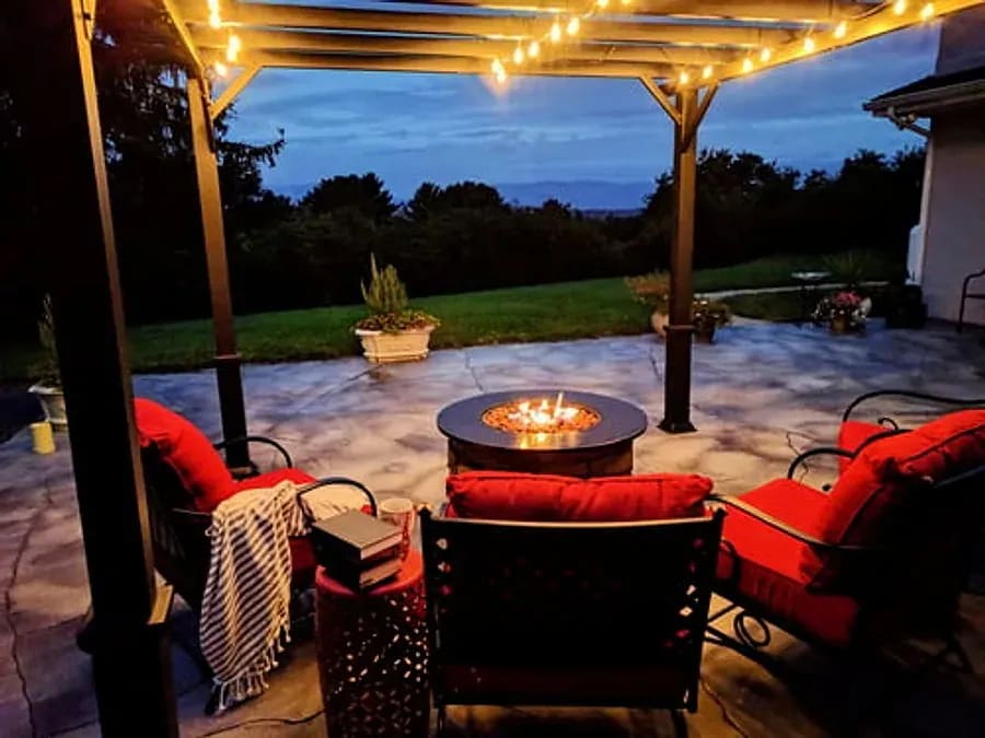 Pergola patio lit with warm string lights and a fire table at dusk in Arizona