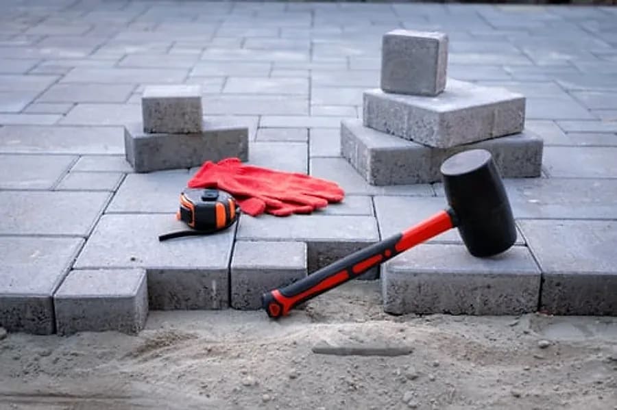 Concrete pavers, rubber mallet and tools during a paver patio installation in Mesa, AZ